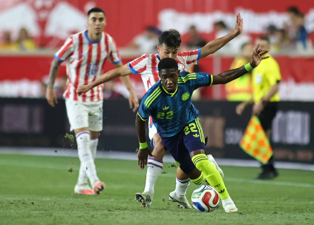 Jugador de Colombia disputa el balón ante Paraguay durante un partido internacional.