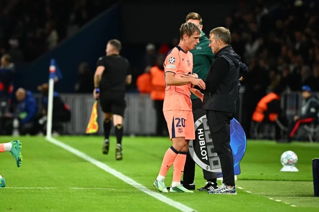 Dani Olmo conversa con Hansi Flick durante el partido ante PSG, antes de confirmarse su lesión que lo deja fuera del Clásico contra Real Madrid.