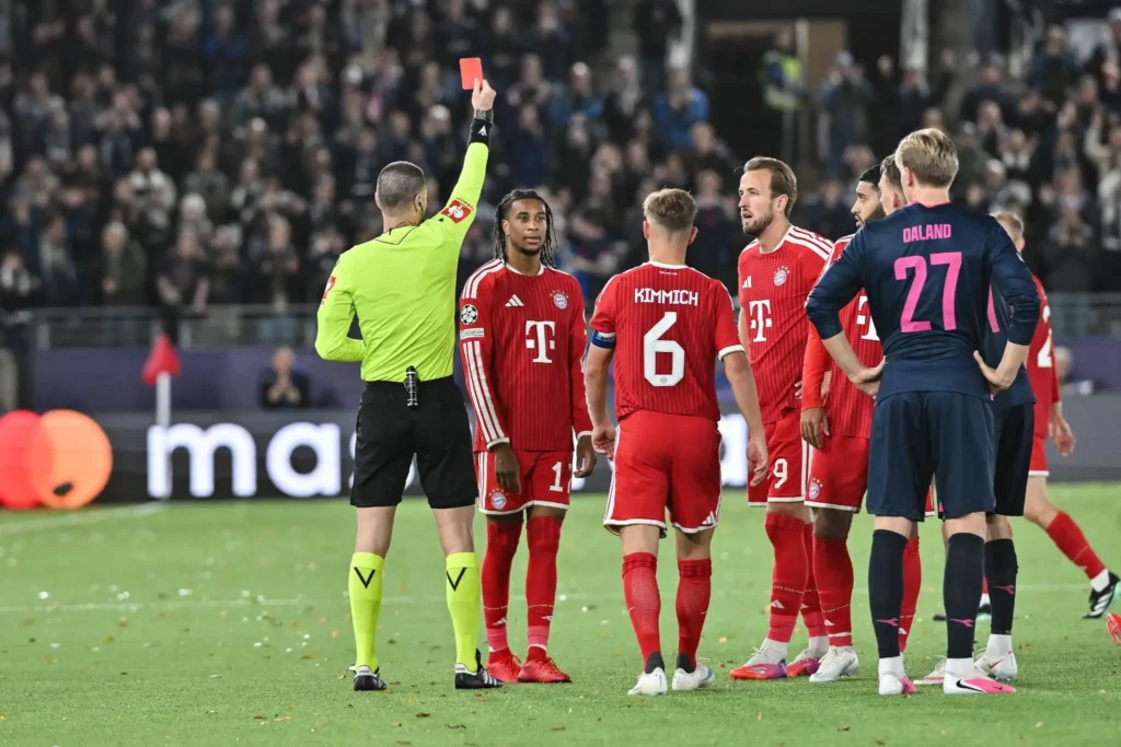 El árbitro muestra la tarjeta roja ante Michael Olise y otros jugadores del Bayern Múnich durante un partido de fútbol.